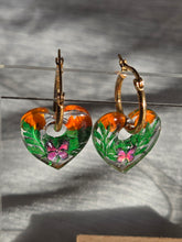 Pampilles en forme de cœurs avec motifs verts et orange, présentées sur des créoles