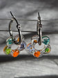 Pampilles translucides en forme de fleurs avec décors orange et verts, présentées sur des créoles