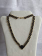 Collier tissé à la main en perles Half Tila noires et rocailles dorées, présenté sur un buste clair