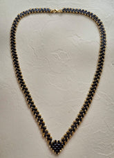 Collier en perles Half Tila noires et rocailles dorées posé à plat, longueur 62 cm et largeur 1 cm