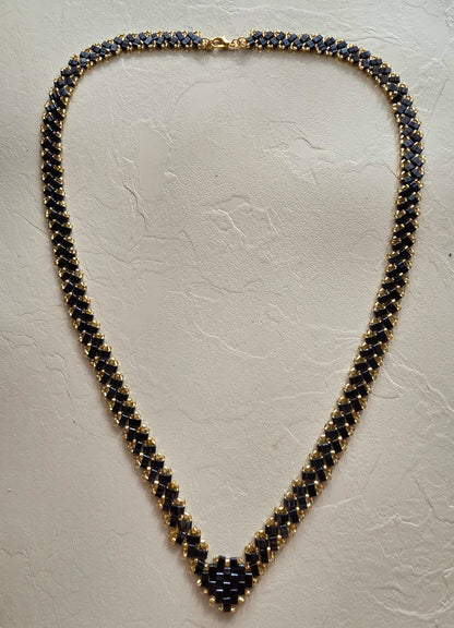 Collier en perles Half Tila noires et rocailles dorées posé à plat, longueur 62 cm et largeur 1 cm
