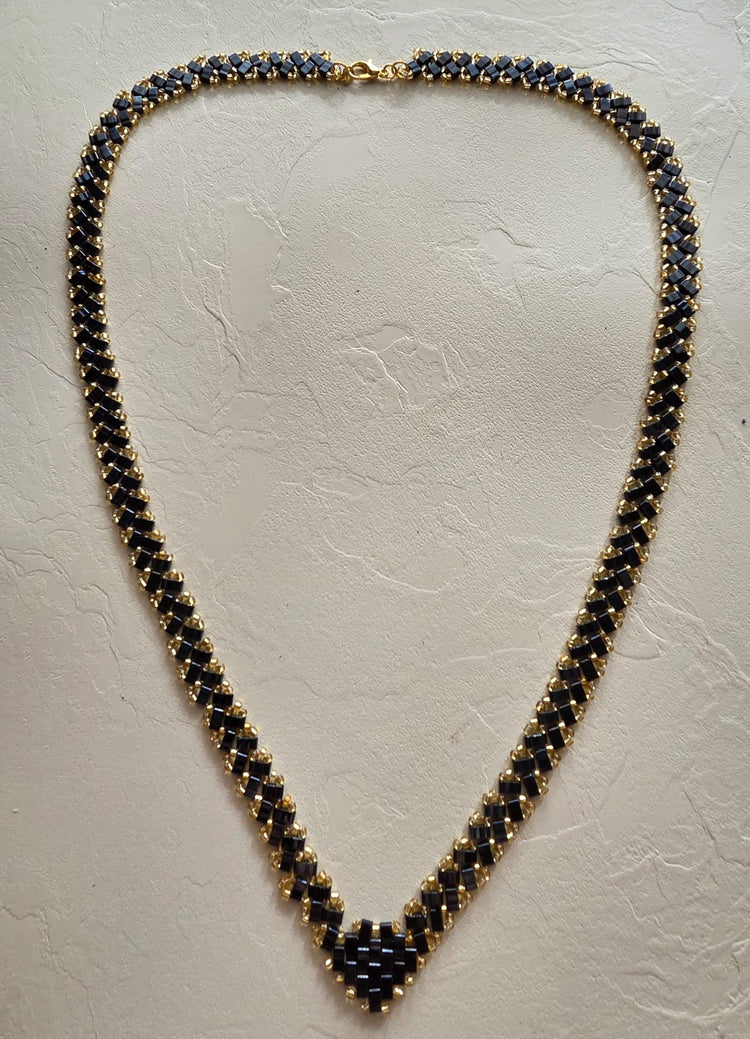 Collier en perles Half Tila noires et rocailles dorées posé à plat, longueur 62 cm et largeur 1 cm